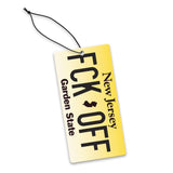 A yellow license plate air freshener with the text 'FCK-OFF Garden State' in black, attached to a black string.